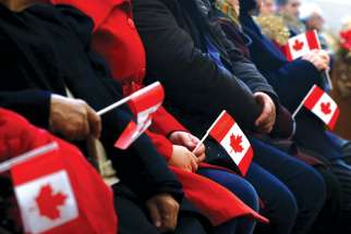 Syrian refugees hold Canadian flags in a welcome service in 2015 at a church in Toronto. Statistics show a dramatic shift in the number of government-assisted refugees versus private sponsorships.