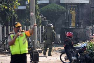 A member of the police bomb squad unit examines the site of a May 12 explosion outside Santa Maria Catholic Church in Surabaya, Indonesia. Christian leaders have called for unity following a spate of suicide bombings that targeted three churches, an apartment building and the police headquarters, the deadliest attacks in more than a decade. 