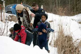 A woman who told police that she and her family were from Sudan is taken into custody by a Royal Canadian Mounted Police officer after arriving by taxi and walking across the U.S.-Canada border into Quebec.