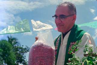 Archbishop Oscar Romero receives a sack of beans from parishioners following Mass outside of the church in San Antonio Los Ranchos in Chalatenango, El Salvador, in 1979. The Mass was held outdoors for fear of possible violence by the Salvadoran military. Before arriving at the church, the archbishop&#039;s delegation was detained by armed military for about 20 minutes.