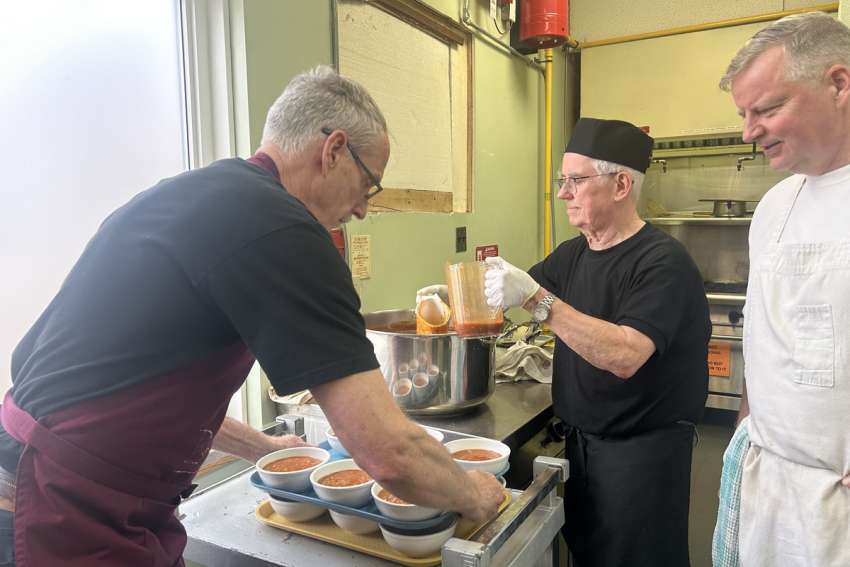 From left, volunteer Dean Yeats and chefs Michael Burns and Gary Marston prepare bowls of tomato and rice soup to be served ahead of the March 18 Community Bread meal.