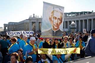 Pilgrims hold a banner of new St. Ludovico Pavoni before the canonization Mass for seven new saints celebrated by Pope Francis in St. Peter&#039;s Square at the Vatican Oct. 16.