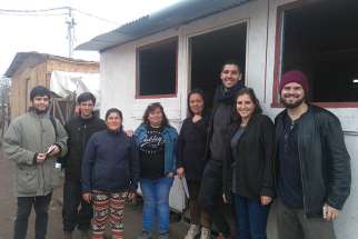  Volunteers from Jesuit-run TECHO-Chile (A Roof for Chile) pose for a photo with community members near a new community center in Rivera Sur camp in Colina, Chile. Young Chileans are discovering that helping others can help them reignite their faith. 
