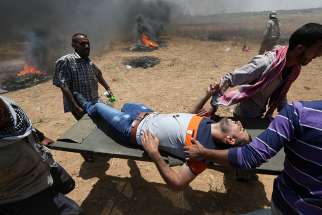 A wounded Palestinian is evacuated at the Israel-Gaza border during a protest against the U.S. embassy move to Jerusalem May 14. 