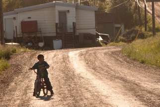 A young boy rides his bike around his neighbourhood in the reserve. 