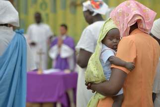 A mother holds her child during Mass in 2014 in Juba, South Sudan. Western governments are &quot;spitting in the face&quot; of African democracy by trying to impose legal abortion against the wishes of most of the people in such countries, a Catholic Nigerian campaigner said.