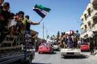  People carry Syrian revolution flags and placards Sept. 14 during protests in Kafr Nabl, Syria.