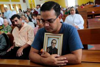 A man holding a portrait of St. Oscar Romero prays during an Oct. 13 Mass at the Metropolitan Cathedral in Managua, Nicaragua. 
