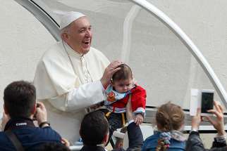 Pope Francis smiles as a papal security guard holds up a baby during his general audience in St. Peter&#039;s Square at the Vatican April 18. 