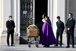 A priest blesses the coffin of a woman who died from COVID-19 in Seriate, Italy, March 28, 2020. The Italian bishops&#039; conference is in discussion with Italy&#039;s Ministry of Internal Affairs about a resumption of public Masses, and especially of funerals.