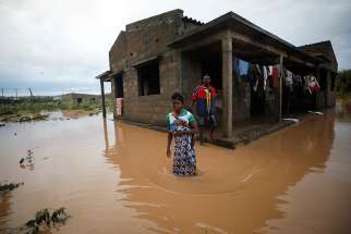 Agiro Cavanda and his wife, Agera, wade through floodwaters outside their home in Pemba, Mozambique, April 29, 2019, in the aftermath of Cyclone Kenneth.