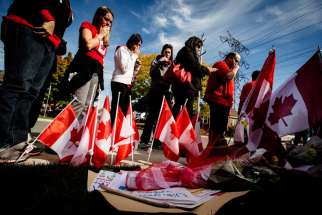 Workers from St. Eugene Catholic School in Hamilton, Ontario, where Cpl. Nathan Cirillo&#039;s son is enrolled, pay respects at a makeshift memorial in honor of Cpl. Cirillo, outside the family home in Hamilton Oct. 24. Cirillo was killed during an Oct. 22 s hooting incident at the Canada War Memorial in Ottawa. 