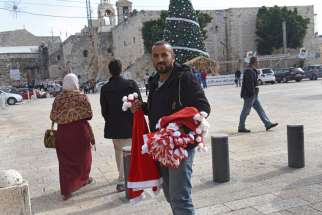 Jasan Zided of Hebron, West Bank, waits to sell Santa hats to tourists in an empty Manger Square Dec. 15 in Bethlehem, West Bank.