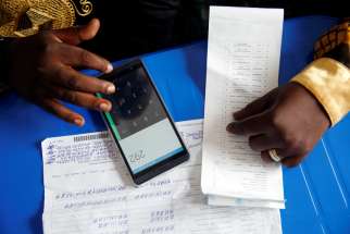 An official of the Congolese Independent National Electoral Commission uses his phone to calculate the numbers of presidential election votes at a tallying center in Kinshasa Jan. 4, 2019. Catholic leaders in Congo have gathered more than 1.5 million signatures on a petition that demands local elections to curb corruption and strengthen democracy.