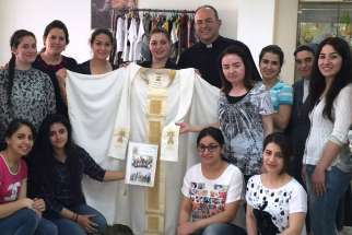 Iraqi refugee women who fled Islamic State group violence in their homeland pose for a photo in Amman, Jordan, in early June. The Chaldean Catholic women sent the hand-sewn mantle to Pope Francis and asked him to pray for them and for peace in their country.