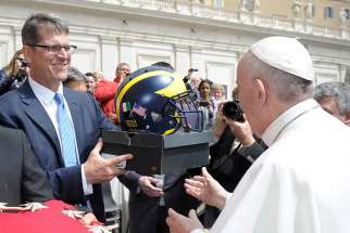 Jim Harbaugh, head football coach for the University of Michigan, presents Pope Francis with a team football helmet during the pope&#039;s general audience in St. Peter&#039;s Square at the Vatican April 26.