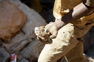 In this Aug. 16, 2016, file photo, an artisanal miner carries raw ore near Kolwezi, Congo. A representative of the Catholic bishops of Congo have called on multinational corporations working in the mineral-rich country to contribute toward local development.