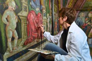 Art restorer Stefania Culesanti puts finishing touches on a red robe in the music section of the Hall of the Liberal Arts in the Borgia Apartments in the Vatican Museums on Dec. 12, 2016.