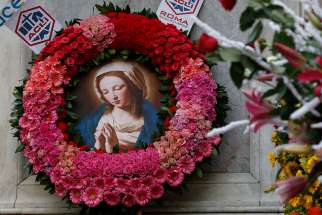 An image of Mary is the centerpiece of a wreath at the base of a Marian statue overlooking the Spanish Steps in Rome Dec. 8, the feast of the Immaculate Conception.