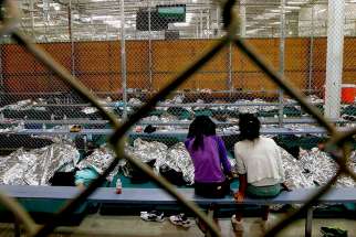 Two young girls watch a World Cup soccer match on a television from a holding area where hundreds of mostly Central American immigrant children are being processed and held at the U.S. Customs and Border Protection Nogales Placement Center in Nogales, Ariz., June 18, 2014.