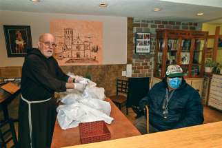 Br. John Corriveau, retired bishop of Nelson, B.C., hands a hot take-out meal to Chico, a regular at St. Francis Table.