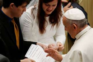 Pope Francis blesses the marriage certificate of a couple during his general audience in Paul VI hall at the Vatican Dec. 14, 2016.
