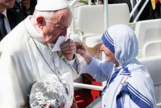 Pope Francis kisses a prayer card presented by a Missionaries of Charity nun at the conclusion of the canonization Mass of St. Teresa of Kolkata in St. Peter&#039;s Square at the Vatican Sept. 4.