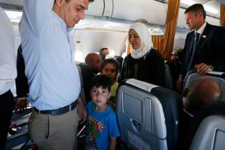 Syrian refugees walk though the aisle of Pope Francis&#039; flight from the Greek island of Lesbos to Rome April 16, 2016. The pope concluded his one-day visit to Greece by bringing 12 Syrian refugees to Italy aboard his flight.