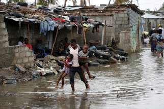 A man carries his children through floodwaters in the aftermath of Cyclone Idai in Beira, Mozambique, March 23. More than two million people in Mozambique, Zimbabwe and Malawi have been affected by a cyclone that has killed more than 700 people, with hundreds still missing in Mozambique and Zimbabwe.