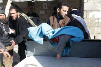 A man carries the body of a child after what activists said were airstrikes by forces loyal to Syrian President Bashar Assad in Damascus Feb. 5. 