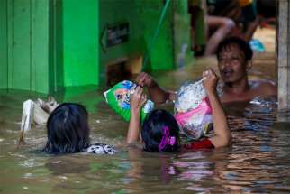 Women carry diapers as they cross a flooded area Jan. 2, 2020, after heavy rains in Jakarta, Indonesia.Caritas Indonesia (Karina) has joined forces with the Jakarta Archdiocese in distributing aid to people hard hit by floods that have killed dozens of people.
