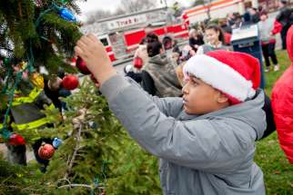 Johnnavin Rodriguez, 11, decorates a Christmas tree outside St. Michael Church in Rochester, N.Y., Dec. 16.