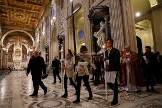 Cardinal Kevin Farrell, prefect of the Dicastery for Laity, the Family and Life, walks behind youths attending a pre-synod meeting as they participate in the Way of the Cross at the Basilica of St. John Lateran in Rome March 23. The meeting is being held in preparation for the Synod of Bishops on young people, the faith and vocational discernment this October at the Vatican