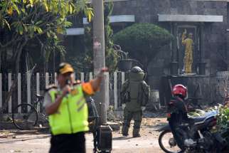 A member of the police bomb squad unit examines the site of a May 13, 2018, explosion outside Santa Maria Catholic Church in Surabaya, Indonesia. Ucanews.com reported Aug. 27 that arrests were made in East Java and that all those arrested were members of the Islamic State-affiliated group Jamaah Ansharut Daulah.