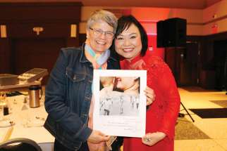 Kim Phuc gives a signed poster to audience member Laurena Hensel that shows the famous photograph during the Focus on Life Gala.