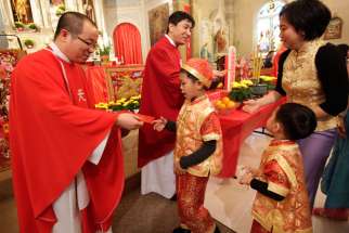 Fathers CheLong Bai and RunBao Zhang pass out red envelopes following Mass at St. Therese Chinese Church in Chicago&#039;s Chinatown at the start of the Chinese lunar new year in 2014.