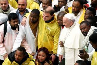 Pope Francis poses with a group of migrants during his general audience Nov. 28 in Paul VI hall at the Vatican.