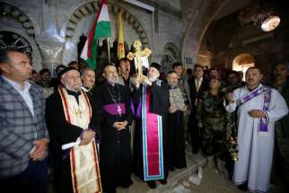 Iraqi Christians take part in a Nov. 19 procession to erect a new cross over a church, after the original cross was destroyed by Islamic State militants in the town of Bartella, Iraq, near Mosul.