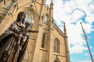 A statue of Mary holding the baby Jesus stands outside St. Michael&#039;s Cathedral Basilica in Toronto.