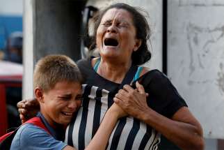 A woman and boy mourn outside a police station jail March 28 in Valencia, Venezuela. At least 68 people, mostly prisoners, were killed in a fire at the jail. 