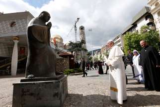 Pope Francis prepares to place flowers at a statue of Mother Teresa at the Mother Teresa Memorial during a meeting with religious leaders and the poor in Skopje, North Macedonia, May 7, 2019. 