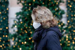  A woman wears a protective mask as she walks past holiday decorations in Rome Dec. 2, 2020. The Italian bishops have said Christmas Eve &quot;midnight Mass&quot; must end before a 10 p.m. nationwide curfew in place by the government to battle COVID-19.