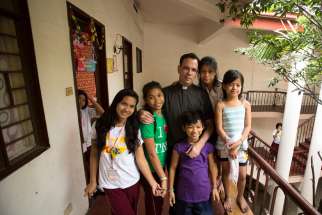 Father Matthieu Dauchez, director of The Blessed Charles de Foucauld Home for Girls, poses with residents Jan. 13 in Manila, Philippines. Father Dauchez said there are between 6,000 to 10,000 street children in metro Manila.