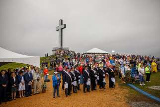 People stand near a 60-foot illuminated cross Aug. 12 at Holy Land USA, a former theme park in Waterbury, Conn., during a Mass honoring sainthood candidate Michael McGivney, founder of the Knights of Columbus and a native of Waterbury.