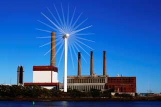 A wind turbine turns in front of a fossil fuel power plant in Charlestown, Mass., in this 2013 file photo. 