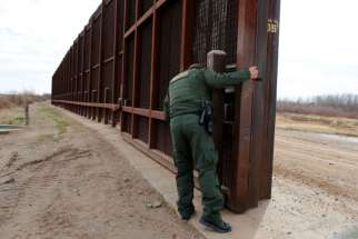 A U.S. Border Patrol agent opens a gate on the fence along the Mexico border to allow vehicles pass Jan. 17 in El Paso, Texas.