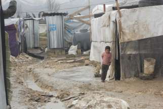 A Syrian child stands barefoot outside a tent Feb. 17 at a camp in Lebanon&#039;s Bekaa Valley. This winter&#039;s heavy rains have caused the paths between the tents at the settlements to fill with water. 