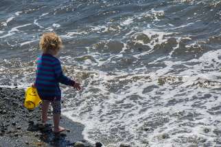 A child walks along the shores of Lake Ontario.