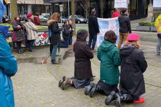 Catholics kneel to pray for churches to open outside Vancouver’s Holy Rosary Cathedral.