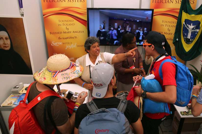 Felician Sister Marget Padilla, who is from the U.S. and ministering in Poland, talks with pilgrims at the World Youth Day evangelization center July 29 in Krakow, Poland.